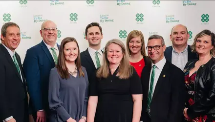 Neuf membres de la Fondation des 4-H du Canada se tiennent debout, souriant, devant la toile de fond des 4-H du Canada