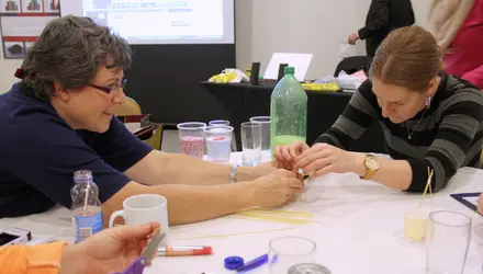 Two adults use craft supplies to complete a science experiment.