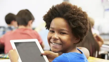 A youth smiles while holding a tablet